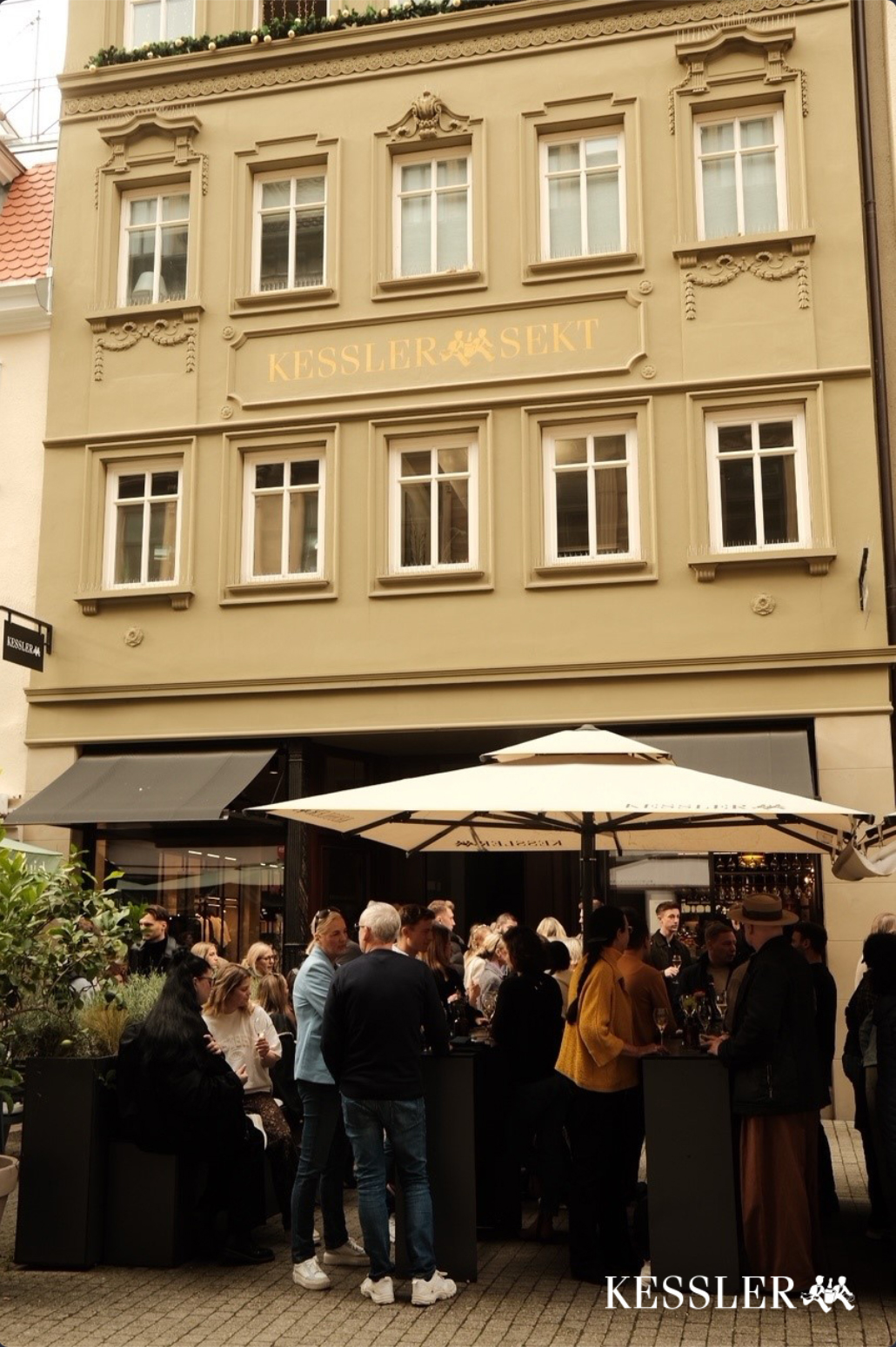 Gruppe von Menschen trinkt Sekt vor dem KESSLER Flagship Store in Stuttgart